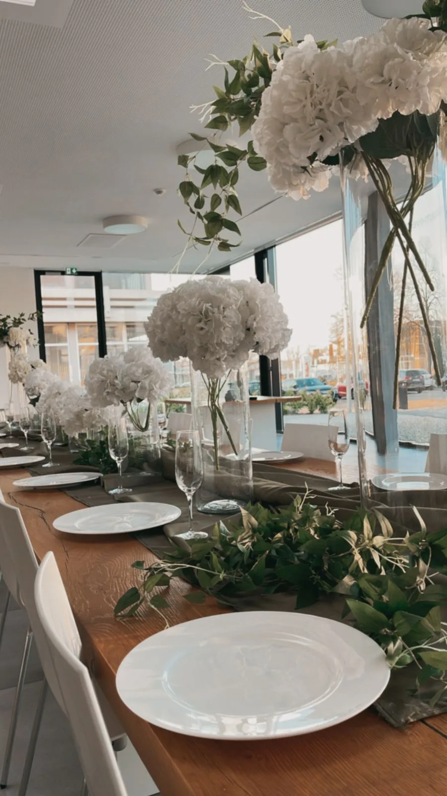 Hochzeitstafel mit Hortensien vor der Glasfront